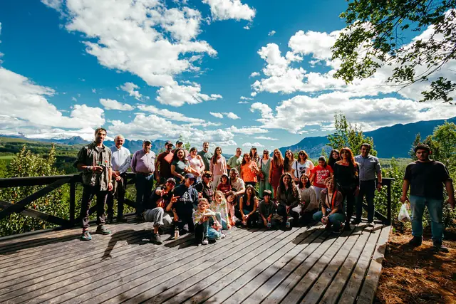 Asistentes reunidos en una terraza de madera con vista a las montañas