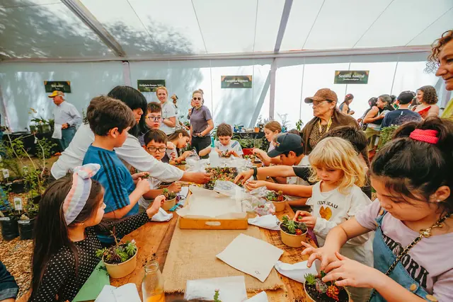 Niños y niñas plantan suculentas en un taller bajo la carpa