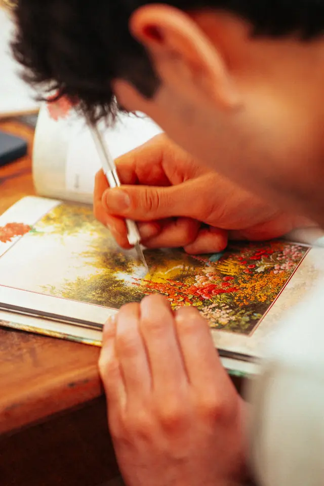 Detalle de una persona pintando una postal botánica